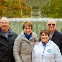 four people smiling by the fountain